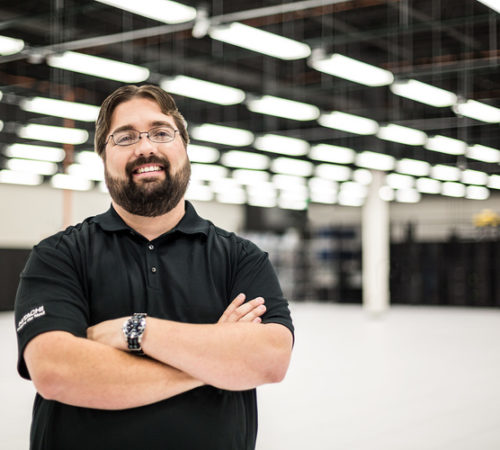 Man with crossed arms smiling in a warehouse