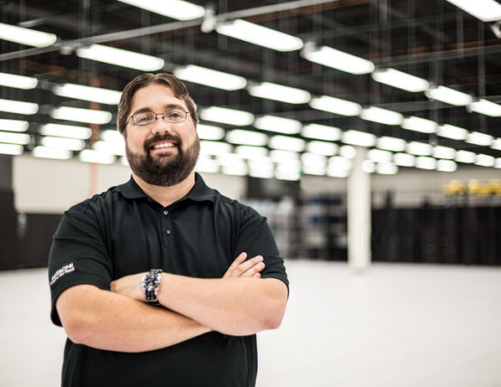 Man with crossed arms smiling in a warehouse